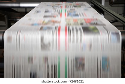 A large offset printing press running a long roll off paper over its rollers at high speed. - Shutterstock ID 92491621