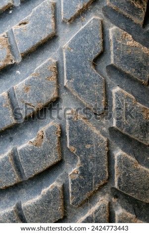 Large old rubber protection. Dirty tread. Textured background. Wheel recycling. Vertical photo. Tractor tire. Deep worn. Repaired tyre. Close-up pattern.