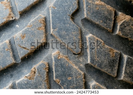 Large old rubber protection. Dirty tread. Textured background. Wheel recycling. Tractor tire. Deep worn. Repaired tyre. Close-up pattern.