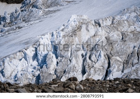 Large open crevasses extend below an active alpine icefall shaped by constant ice movement. The image illustrates the dynamic transition between stable glacier surfaces and heavily fractured terrain.