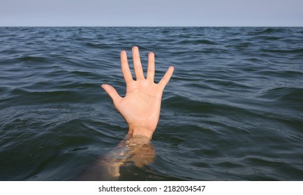 Large Open Hand With Five Fingers Emerging From The Surface Of The Sea Of A Person About To Drown Under Water