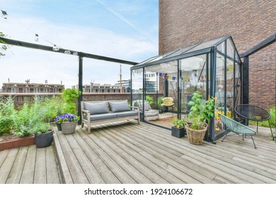 A large open-air terrace on the roof-top with lounge space and a small greenhouse with plants - Shutterstock ID 1924106672