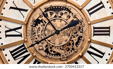 A large, open-faced wall clock with a distressed gold-wash metal finish and exposed, moving 3D gears. Close up of elegant Antique clock featuring roman numerals, classic design.