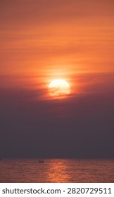 Large Orange Sun Setting Over the Sea with a Small Boat