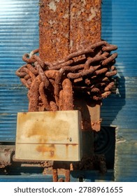 A large padlock with a rusty chain attached to the handle of the old gate