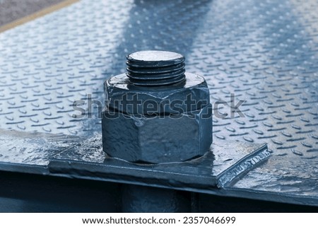 large painted grey threaded bolt and nut. welded checkered plate. bridge construction. closeup view. counter nut. part of the renovated famous Chain Bridge in Budapest. engineering concept.