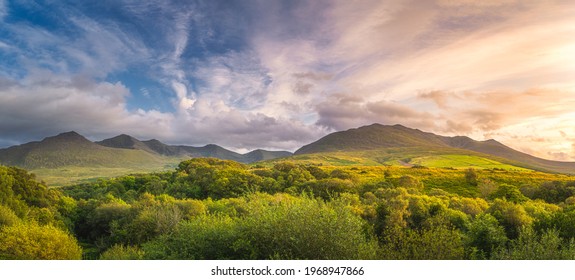 Large panorama with amazing sunset and dramatic sky with sunlight illuminating the foothill of Carrauntoohil mountain at MacGillycuddys Reeks mountains, Ring of Kerry, Ireland - Powered by Shutterstock