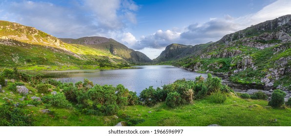 Large panorama with Black Lake valley and mountains at sunset in Gap of Dunloe, Black Valley, MacGillycuddys Reeks mountains, Ring of Kerry, Ireland - Powered by Shutterstock