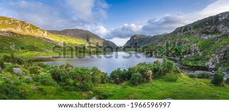 Large panorama with Black Lake valley and mountains at sunset in Gap of Dunloe, Black Valley, MacGillycuddys Reeks mountains, Ring of Kerry, Ireland