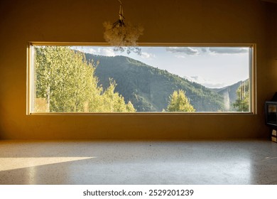 Large panoramic window offering a stunning view of lush green hills and forests. Natural light fills the room, creating a peaceful atmosphere that connects the interior to the beauty of nature