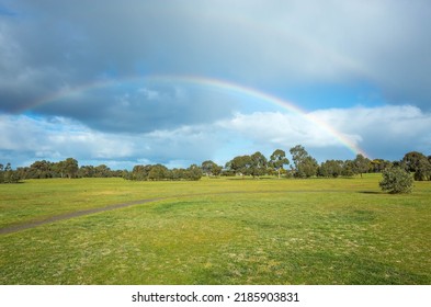 A Large Park With Double Rainbows Against Cloudy Sky. Background Texture Of Green Grass Field Or Meadow With Australian Native Trees And A Small Footpath. Copy Space For Text. Presidents Park Werribee