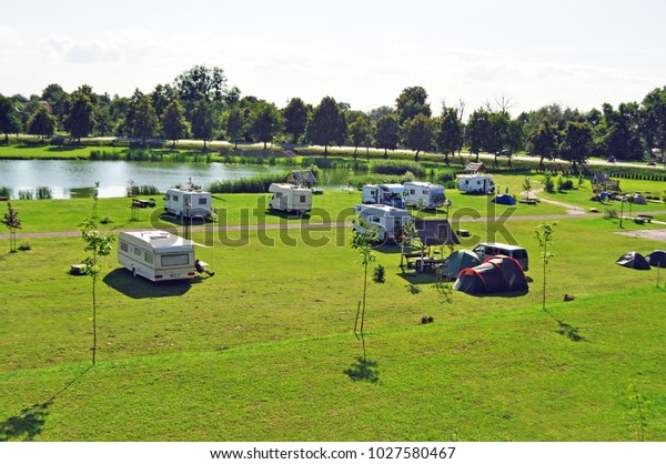 large Parking lot on a green meadow\
near the lake shore for mobile homes, campers,\
trailers