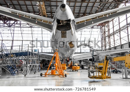 Large passenger aircraft on service in an aviation hangar rear view of the tail, on the auxiliary power unit