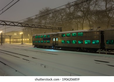 Large Passenger Train Car With Green Windows At Rest In The Snow On Overcast Night In Urban Chicago