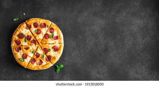 Large Pepperoni and Mozzarella Pizza on black table, top view, copy space. Delicious fresh baked pizza.