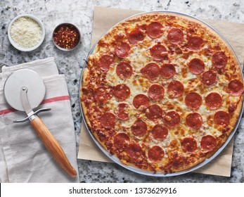 Large Pepperoni Pizza On Marble Counter In Overhead Flat Lay Composition