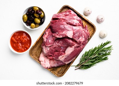 A large piece of raw meat set, with ingredients and herbs, on white stone table background, top view flat lay