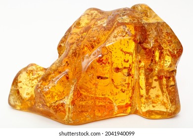 A Large Piece Of Transparent Yellow Amber On A White Background. Resin Inclusions. Insects And Bubbles In The Sun Stone. Material For Jewelers. Copal. Fossilized Ancient Mineral. Colored Crystal 