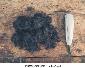 A Large Pile Of Cut Hair And Some Clippers On A Wooden Table