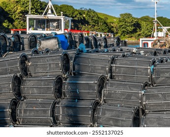 A large pile of fishing nets and traps is stacked by the riverside, with lush greenery and a clear blue sky in the background, depicting a serene and industrious scene. - Powered by Shutterstock