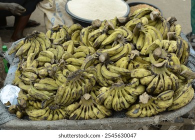 A large pile of green plantains on display at an outdoor market, capturing the abundance of fresh, tropical produce ready for sale in a vibrant street setting. - Powered by Shutterstock