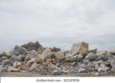 A large pile of limestone rubble against the cloudy sky.