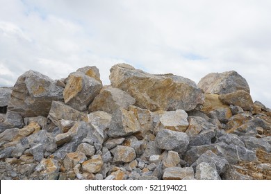 A large pile of limestone rubble against the cloudy sky.