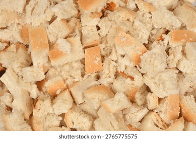 A large pile of small white bread cubes with golden crusts filling the frame for food preparation or crouton making