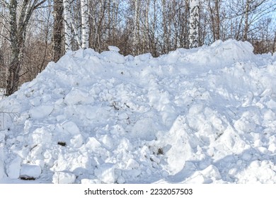 large pile of snow collected by snowplow after clearing road. Snow cleaning in winter in city