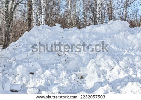 large pile of snow collected by snowplow after clearing road. Snow cleaning in winter in city