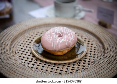 Large Pink Doughnut With White Icing On Wicker Plate