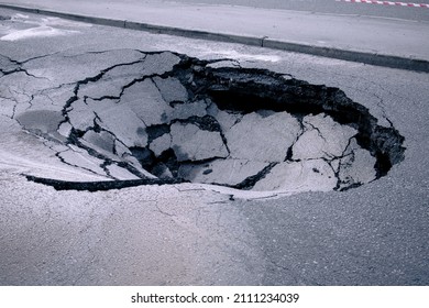 A Large Pit In The Asphalt Due To A Pipeline Accident. A Hole In The Ground In The Middle Of The Road. Asphalt That Has Collapsed Underground