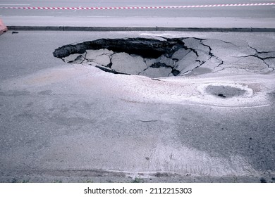 A Large Pit In The Asphalt Due To A Pipeline Accident. A Hole In The Ground In The Middle Of The Road. Asphalt That Has Collapsed Underground