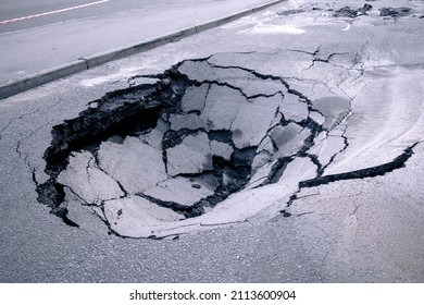 A Large Pit In The Asphalt Due To A Pipeline Accident. A Hole In The Ground In The Middle Of The Road. Asphalt That Has Collapsed Underground