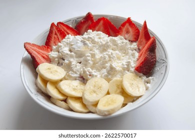 Un Grande plato de queso cottage y fruta para desayunar. Un plato saludable para una dieta saludable. Un desayuno saludable consiste en queso cottage, plátanos y fresas. Nutrición dietética, comida para bebés.