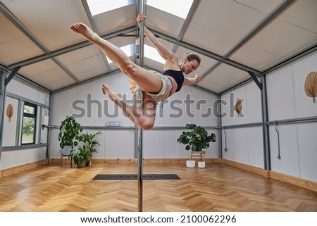 large pole dance studio with dancing instructura suspended in the air.