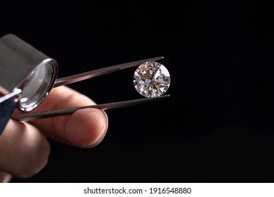 Large polished round cut diamond in hand close up front view. High quality photo