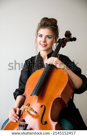 a large portrait of a girl with a cello, a cellist sits with a cello in her hands and looks at the camera