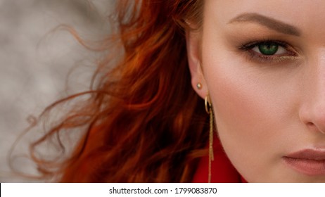 A large portrait of a young red-haired woman with bright makeup and green eyes. Part of the face close up - Powered by Shutterstock