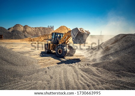 A large powerful loader overloads a pile of rubble in a concrete plant.