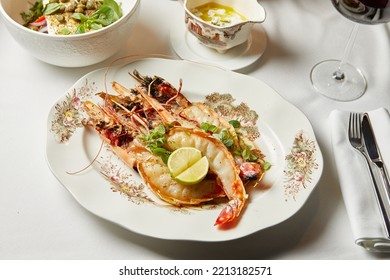 Large Prawns With Lime And Greens In A White Plate During Dinner In A Restaurant