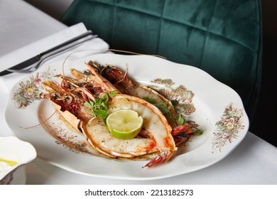 Large Prawns With Lime And Greens In A White Plate During Dinner In A Restaurant