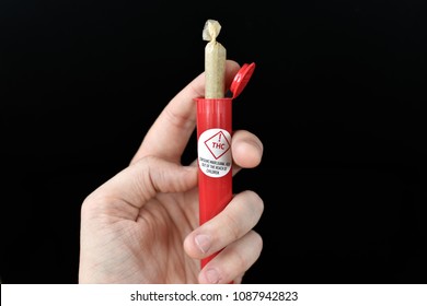 Large Pre Rolled Joint Sticking Out Of Red Tube. THC Sticker With Warning To Keep Away From Children Can Also Be Seen.