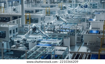 Large Production Line with White Industrial Robot Arms at Modern Bright Factory. Solar Panels are being Assembled on Conveyor. Automated Manufacturing Facility.