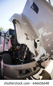 A Large Professional American Model Big Rig Beige Semi Truck Crashed In A Car Accident Stands With An Open Damaged Hood With Red Engine And A Crumpled Body On Parking Lot