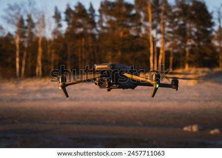 A large professional drone with a camera in flight in nature, on the seashore. 