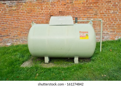 A Large Propane Tank Against A Red Brick Wall