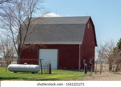 A Large Propane Tank In Front Of A Barn On Farm Land.