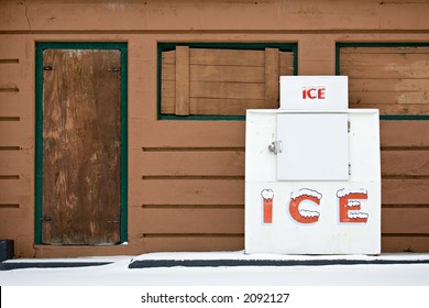 Large Public Ice Chest Outdoors Against Old Brown Building And With Snow In Foreground.