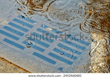 Large puddle due to clogged storm drain. Flooding across road during rain, blocked street drain. Plumbing problems in the city, clogged drain, water flooding. Selective focus